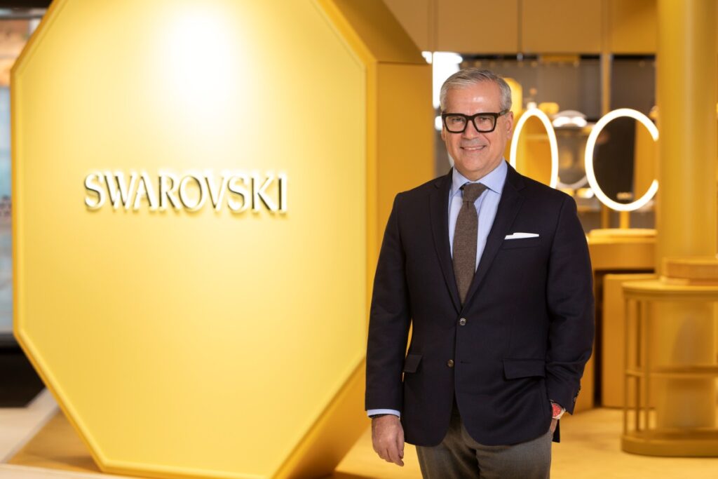 Ubrany w garnitur CEO marki Swarovski stojący na żółtym tle