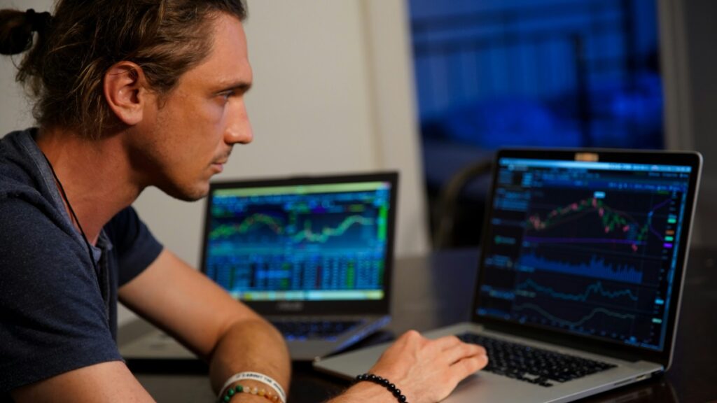 Mężczyzna wpatrzony w ekran komputera, na którym wyświetlane są wykresy