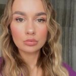 Ujęcie portretowe. Kadr skierowany na twarz młodej kobiety. Blondynki z kręconymi włosami.