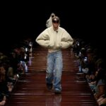 Kadr z pokazu mody marki Balenciaga. Mężczyzna kroczy przez catwalk w oversize'owych jeansach oraz białej kurtce. Czy z tego obrazu można wyciągnąć wskazówki dla polskich marek na 2025 rok?