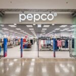 Szyld obrazuje wejście do sklepu stacjonarnego brytyjskiego giganta, który przedstawił raport. Wyniki finansowe Pepco, współgrają z jej rosnącym asortymentem. Na zdjęcie znajduje się białe logo firmy znajdujące się nad wejściem do salonu.