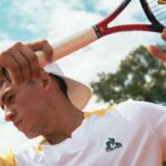 Le Coq Sportif to marka, która towarzyszy francuskim sportowcom od ponad 130 lat. Na zdjęciu tenisista w polówce marki, trzymający w ręku rakietę tenisową.