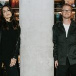 Kaja Wrzeszcz, dyrektorka marketingu PRM, i Kamil Bajołek, dyrektor PRM. Zdjęcie zrobione na tle ściany pełnej płyt winylowych. Mężczyzna ubrany jest w czarną koszulę, natomiast kobieta ma na sobie ciemny garnitur.
