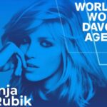 Plakat w odcieniach niebieskiego przedstawiający Anję Rubik, z podpisem 'Anja Rubik' w lewym dolnym rogu. W prawym górnym rogu znajduje się tekst 'World Woman Davos Agenda'. Anja ma długie, rozpuszczone włosy i podpierając głowę dłonią, patrzy w dal.