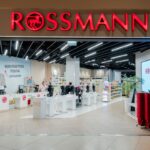 Zdjęcie przedstawia nowoczesne wnętrze drogerii Rossmann, z elegancko zaprojektowanymi kasami oraz jasno oświetlonymi regałami pełnymi produktów. Wystrój sklepu podkreśla dbałość firmy o estetykę i wygodę klientów. Tego typu placówki są istotnym elementem sukcesu i rekordowych wyników sieci Rossmann, które w 2024 roku osiągnęły historyczne obroty.
