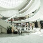 Najlepsze galerie handlowe w Polsce. Zdjęcie przedstawia centrum handlowe. Widać na nim schody ruchome, sklepy, recepcję i kolejne piętra. Wnętrze jest utrzymane w jasnej kolorystyce.