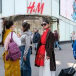 Wyniki finansowe H&M Q1 2025. Na zdjęciu trzy kobiety stoją przed wejściem do sklepu h&m.