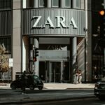 Zara Streaming. Zdjęcie przedstawia wejście do sklepu Zara. Widoczne są samochody, światła, ludzie idący chodnikiem oraz duży szyld z nazwą ZARA.