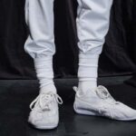 Puma Speedcat. Zdjęcie przedstawia zbliżenie na nogi modela. Mężczyzna ma na sobie białe dresy i białe wysoko naciągnięcie skarpety. Widać również białe buty Puma Speedcat Ultrasoft, będące efektem współpracy Pumy i Balenciagi.