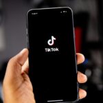 TikTok Shop w Polsce. Zdjęcie trzymanego w ręce telefonu z logo aplikacji TikTok.