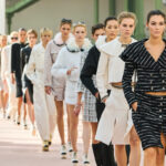 Krzyżówka o modzie dostępna na Fashion Biznes. Na zdjęciu modelki na pokazie Chanel w eleganckich, monochromatycznych stylizacjach idą po wybiegu.
