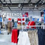 LPP inwestuje w markę Sinsay. Zdjęcie przedstawia wnętrze sklepu Sinsay, widać wieszaki z ubraniami i duży napis na ścianie "Trends".