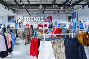 LPP inwestuje w markę Sinsay. Zdjęcie przedstawia wnętrze sklepu Sinsay, widać wieszaki z ubraniami i duży napis na ścianie "Trends".