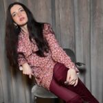 Nalu Bodywear – likwidacja marki! Zdjęcie przedstawia modelkę z długimi ciemnymi włosami, pozującą w różowej sukience w kwiaty oraz bordowych rajstopach i butach nad kolano.
