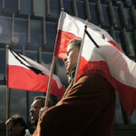 Żałoba narodowa w Polsce 26 kwietnia 2025. Co ozncza - czy sklepy będą otwarte? Na zdjęciu ludzie idący z flagami Polski, oznaczonymi czarnymi wstążkami na znak żałoby narodowej.