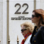 Kobiety przechodzą obok logo LVMH Moët Hennessy Louis Vuitton przed siedzibą główną grupy luksusowej LVMH w Paryżu, Francja, 14 kwietnia 2025 r.