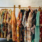 Czysta moda, czyli clean fashion. Zdjęcie przedstawia kolorowe ubrania wiszące na wieszaku z naturalnego materiału.