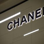 Logo luksusowej marki Chanel, która właśnie poinformowała o spadku sprzedaży i wynikach finansowych 2024. Czarny napis na jasnym tle z widocznym podświetleniem.