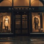 Sklep Burberry wieczorem, z podświetloną ekspozycją, szyldem z nazwą marki i kratami chroniącymi drzwi.