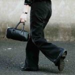 Problemy eobuwie.pl zamówienia opóźnione, brak zwrotu pieniędzy. Na zdjęciu zbliżenie na tył kobiety idącej ulicą, trzymającej w ręce czarną torebkę.