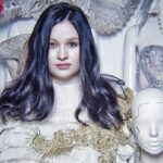 Kim jest Katarzyna Konieczka? Życiorys i kariera. Porter bohaterki artykułu – kostiumografki i projektantki, Katarzyny Konieczki. Kobieta pozuje w ciemnych rozpuszczonych włosach z głową manekina.