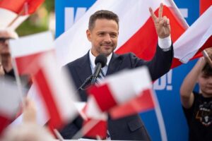 Jak głosowali przedsiębiorcy? Na zdjęciu Rafał Trzaskowski wykonujący znak pokoju, stoi wśród polskich flag. To kandydat na Prezydenta RP, który zdobył najwięcej głosów przedsiębiorców w wyborach 2025.