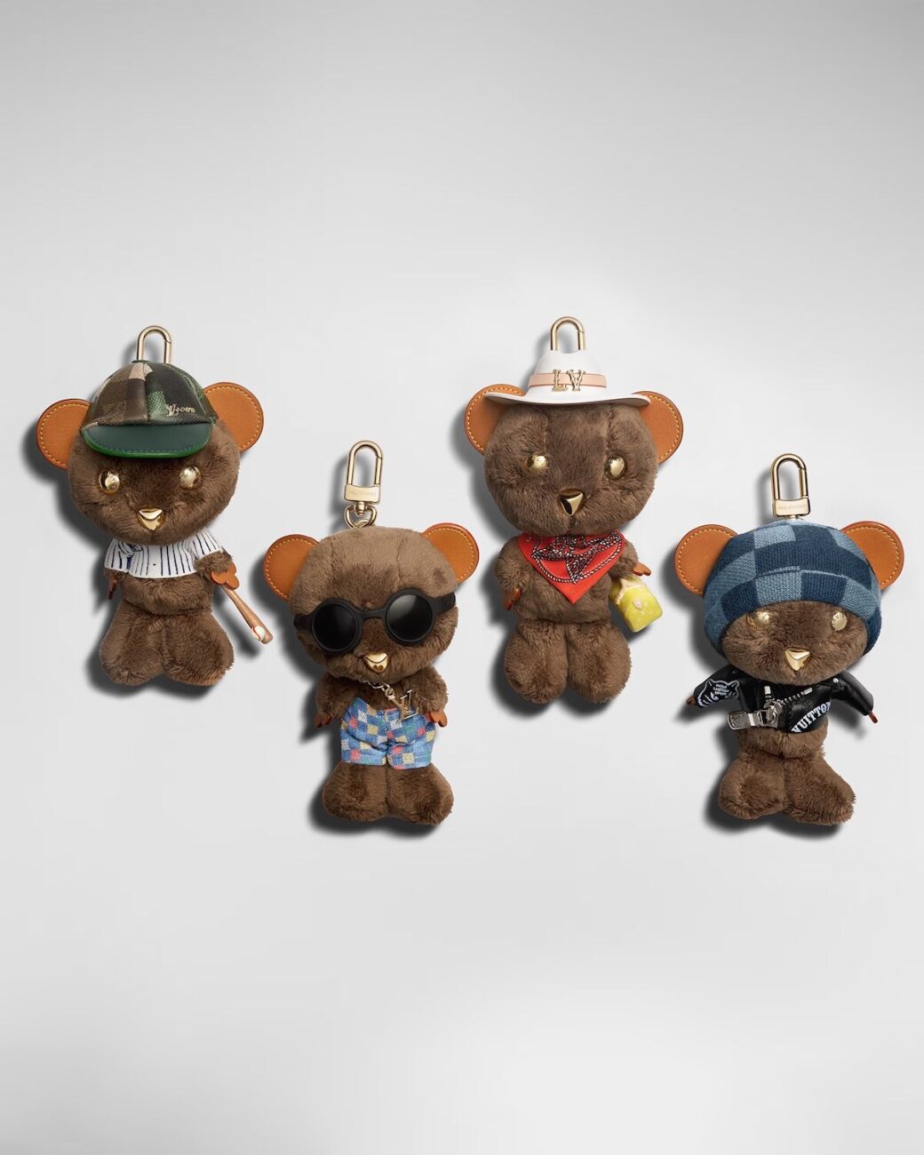 Zdjęcie 4 breloków Louis Bear z kolekcji Louis Vuitton. Breloki są ustawione w rzędzie – dwa wyżej, dwa niżej. Mają różne czapki i stroje.
