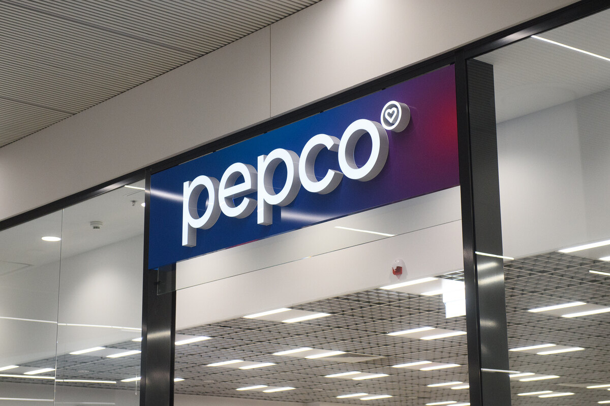 Szyld sklepu Pepco, należącego do Grupy Pepco, która sprzedała właśnie Poundland – sieć dyskontową. Szyld jest niebiesko-fioletowy, z płynnym przejściem kolorów. Z kolei napis jest biały. Oprócz tego na zdjęciu widać sufit sklepu z lampami.