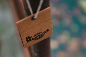 Zdjęcie przedstawiające zbliżenie na metkę Dr. Martens, wiszącą na jasnym sznurki.