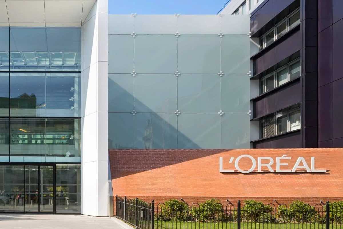 Nowoczesny budynek L'Oréal z przeszkloną fasadą i logotypem firmy na czerwonej ceglanej ścianie.