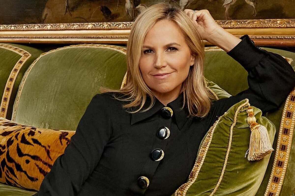 Najbogatsze self-made kobiety w Ameryce 2025. Na zdjęciu jedna z nich: projektantka Tory Burch, właścicielka luksusowej marki. Kobieta ma blond włosy do ramion, nosi czarny żakiet z dużymi guzikami. Siedzi na zielonej kanapie.