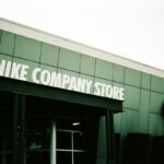 Zwolnienia w Nike. Zdjęcie zielonego budynku z białym szyldem "Nike Company Store" i pomarańczowym logo amerykańskiej marki.
