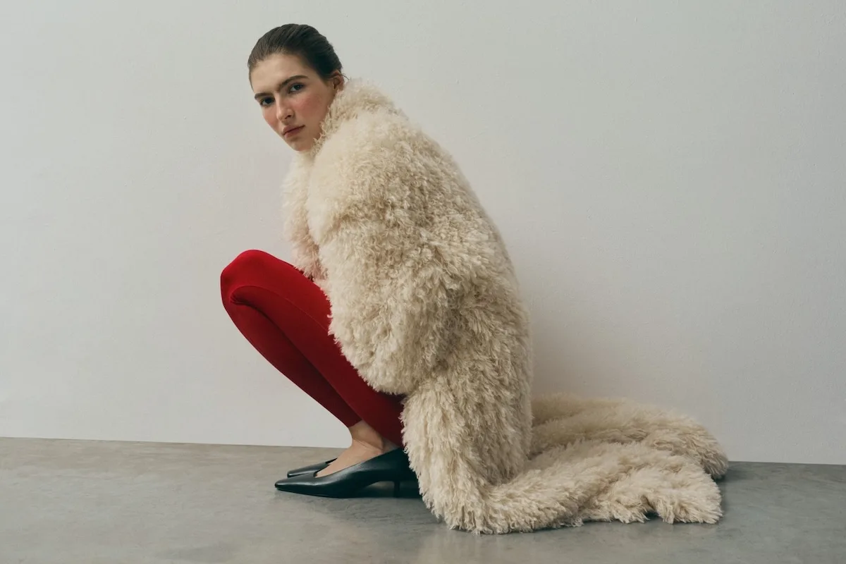 Kampania marki L37 - modelka w białym futrze i czerwonych legginsach kuca, patrząc się w obiektyw.