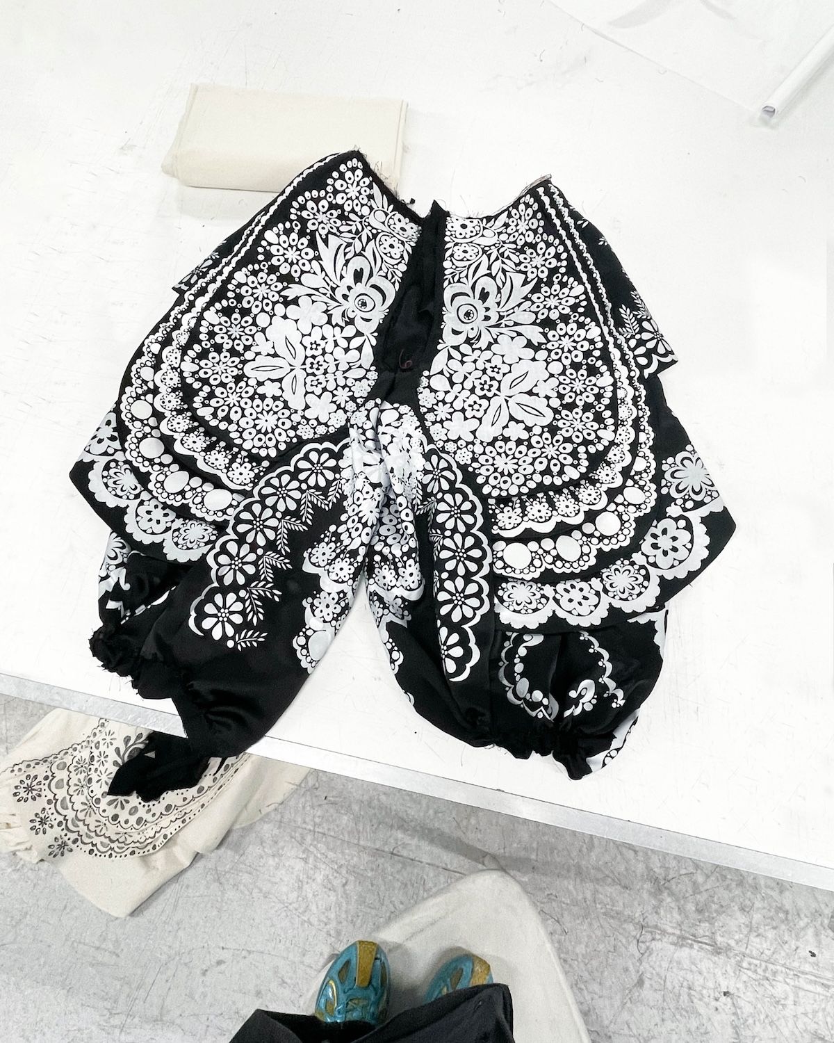 Fragment projektu z kolekcji dyplomowej Huberta Pelca inspirowanej polskim folklorem. Czarno-białe spodnie zdobione bogatym, ornamentalnym printem nawiązują do tradycyjnych haftów ludowych. Projekt pokazuje, jak młody projektant interpretuje rzemiosło w nowoczesnej modzie.