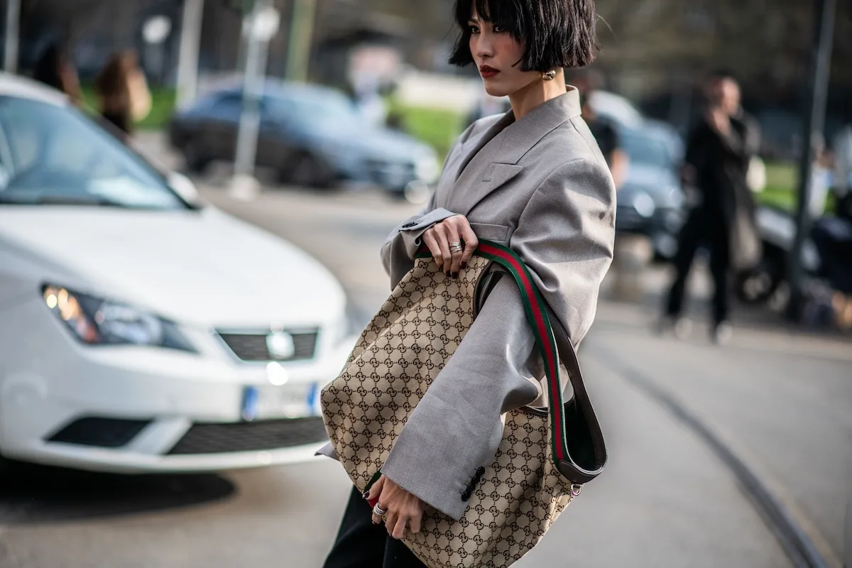 Torebka Gucci z charakterystycznym wzorem GG noszona do oversize’owej marynarki w stylu street style. W przypadku takich modeli z drugiej ręki znaczenie ma m.in. certyfikat Entrupy.