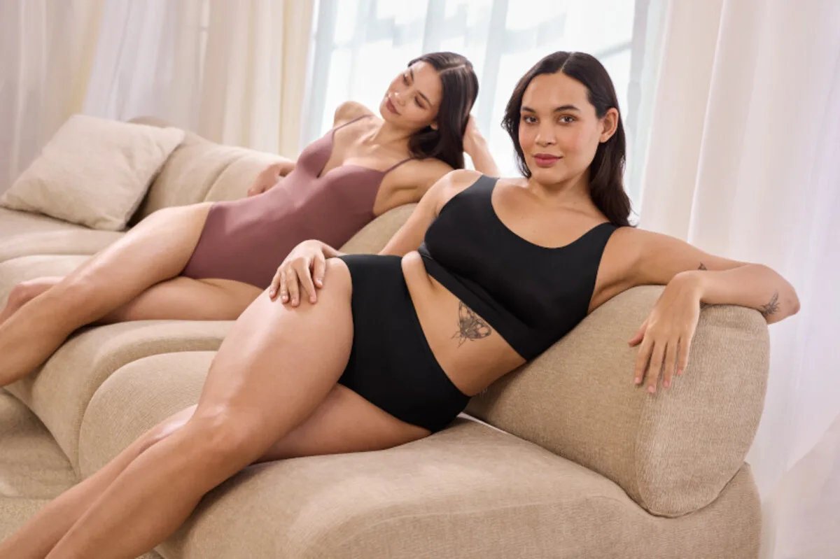 Restrukturyzacja The Lycra Company. Dwie kobiety w dopasowanej bieliźnie z elastycznego materiału, siedzące na kanapie w jasnym wnętrzu.