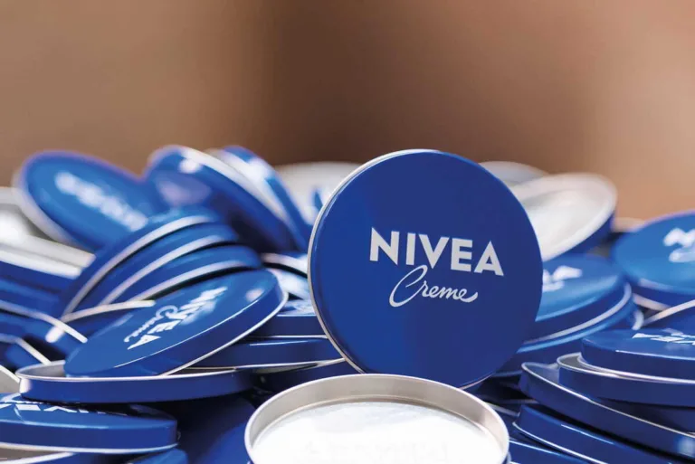 Kultowe opakowania kremu Nivea w niebieskich metalowych puszkach ułożone w stos. Obraz przedstawia jeden z najbardziej rozpoznawalnych produktów firmy, która została ukarana przez urząd za opóźnienia w rozliczeniach z kontrahentami.