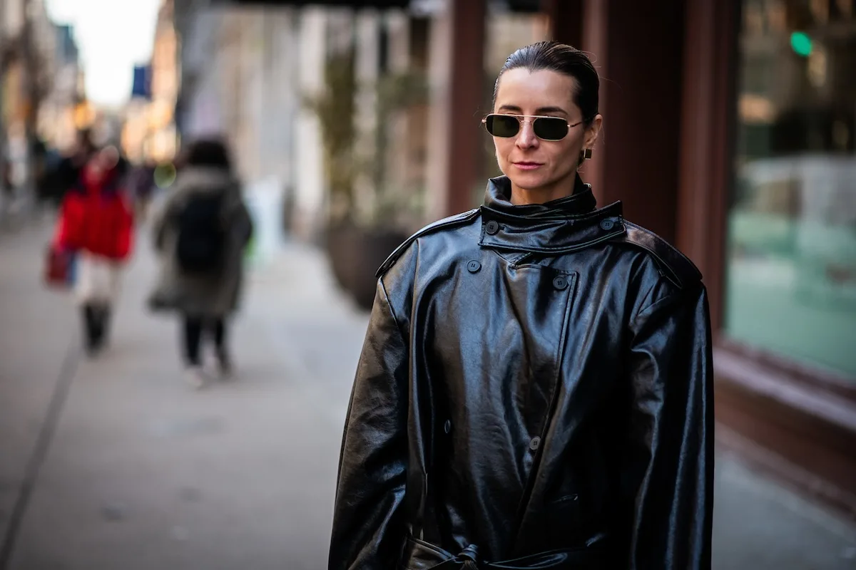 Kobieta w czarnym płaszczu spaceruje ulicą miasta podczas zwolnienia lekarskiego L4 – przykład dozwolonej aktywności zgodnej z zaleceniami lekarza. Nowe przepisy 2026 zaostrzają kontrole ZUS, które mogą ocenić, czy takie wyjście nie wpływa negatywnie na proces leczenia.