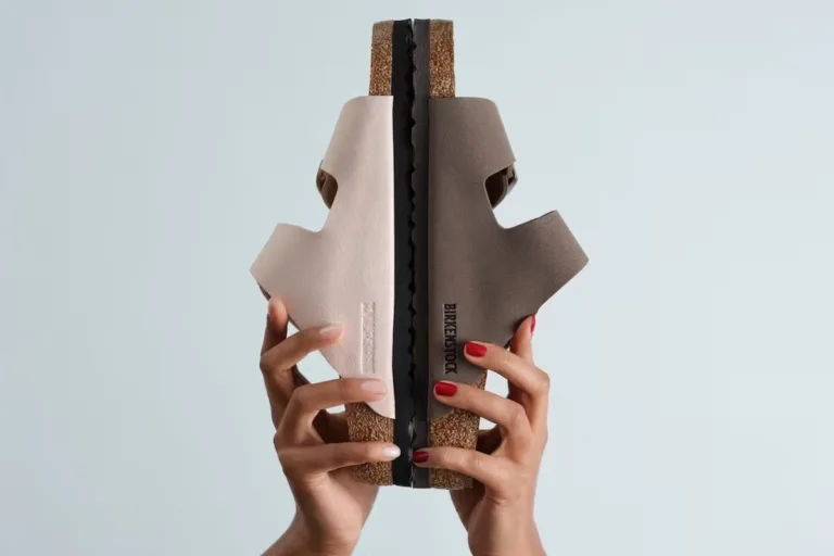 Birkenstock wprowadza lakiery do paznokci do oferty. Na zdjęciu dłonie z paznokciami pomalowanymi nowymi lakierami trzymające klapki Arizona, inspirację do stworzenia produktu.