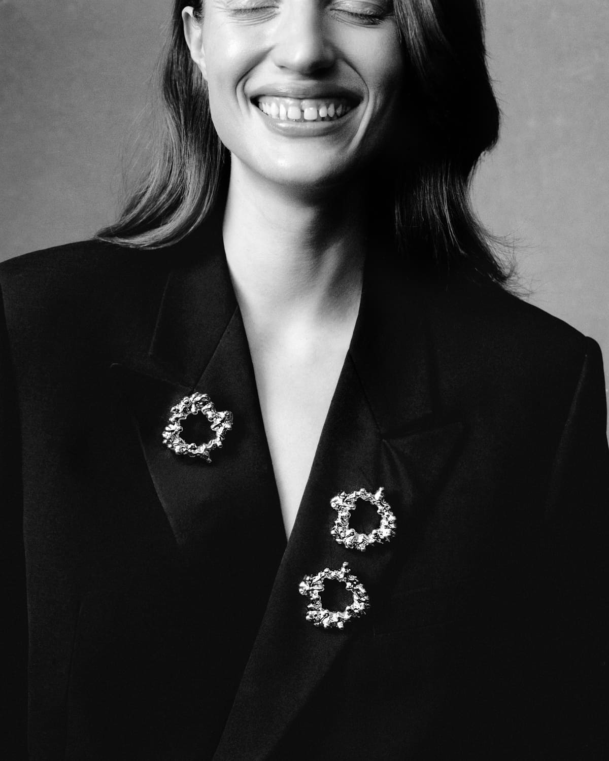 Modelka w czarnym garniturze z broszkami CHYLAK Jewellery inspirowanymi strukturą sękacza