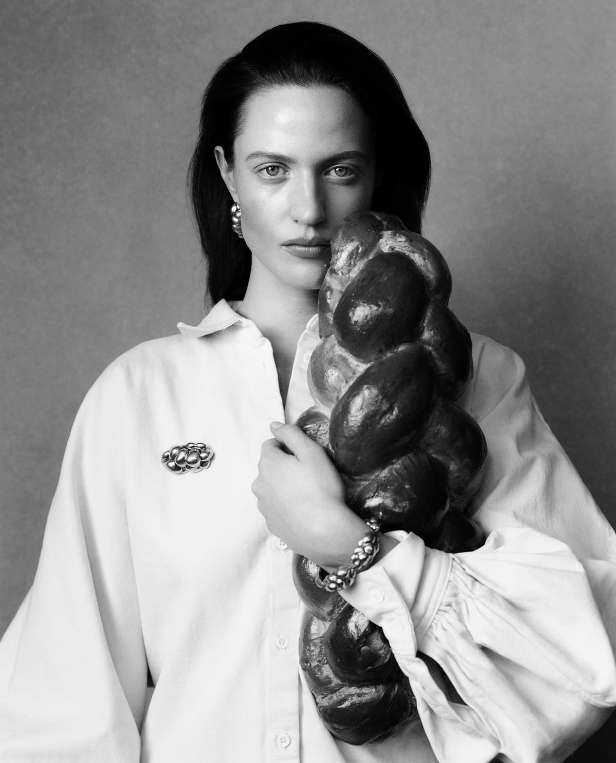 Modelka z chałką w rękach prezentująca biżuterię CHYLAK Jewellery inspirowaną plecioną formą wypieków