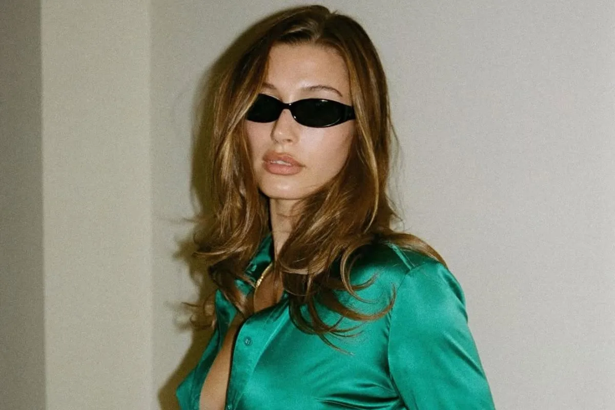 Hailey Bieber w stylizacji inspirowanej latami 90., zestawionej z charakterystycznymi wąskimi okularami. Jej estetyka często łączy elementy vintage – jak kurtki Lotto Sport Italia – z nowoczesnym minimalizmem. To właśnie takie looki wpływają na powrót zapomnianych marek do trendów.