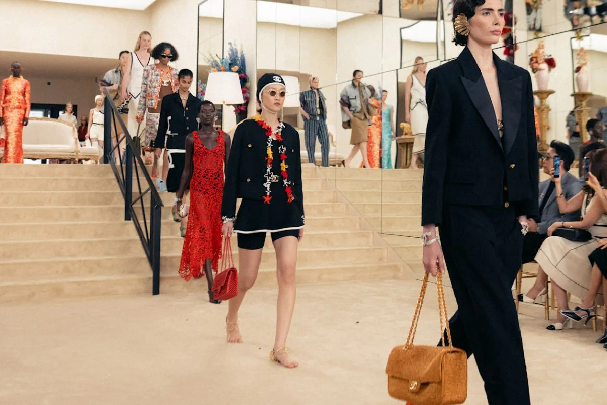 Viralowe sandały z samą piętą Chanel. Modele schodzące po schodach podczas pokazu Chanel Cruise 2027, prezentujące eleganckie sylwetki i charakterystyczne dodatki maison. Na pierwszym planie widać stylizacje uzupełnione o sandały z samą piętą Chanel, które nadają efekt niemal bosej stopy. To właśnie te sandały z samą piętą Chanel przyciągnęły największą uwagę widzów i wywołały dyskusję w sieci.