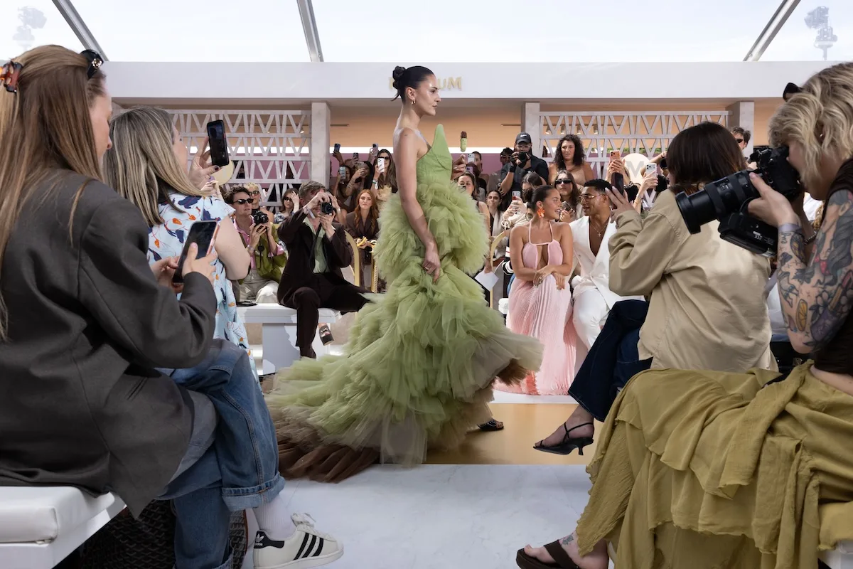 Modelka w zielonej, warstwowej sukni couture inspirowanej pistacjowym Magnum idzie po wybiegu podczas pokazu House of Magnum w Cannes.