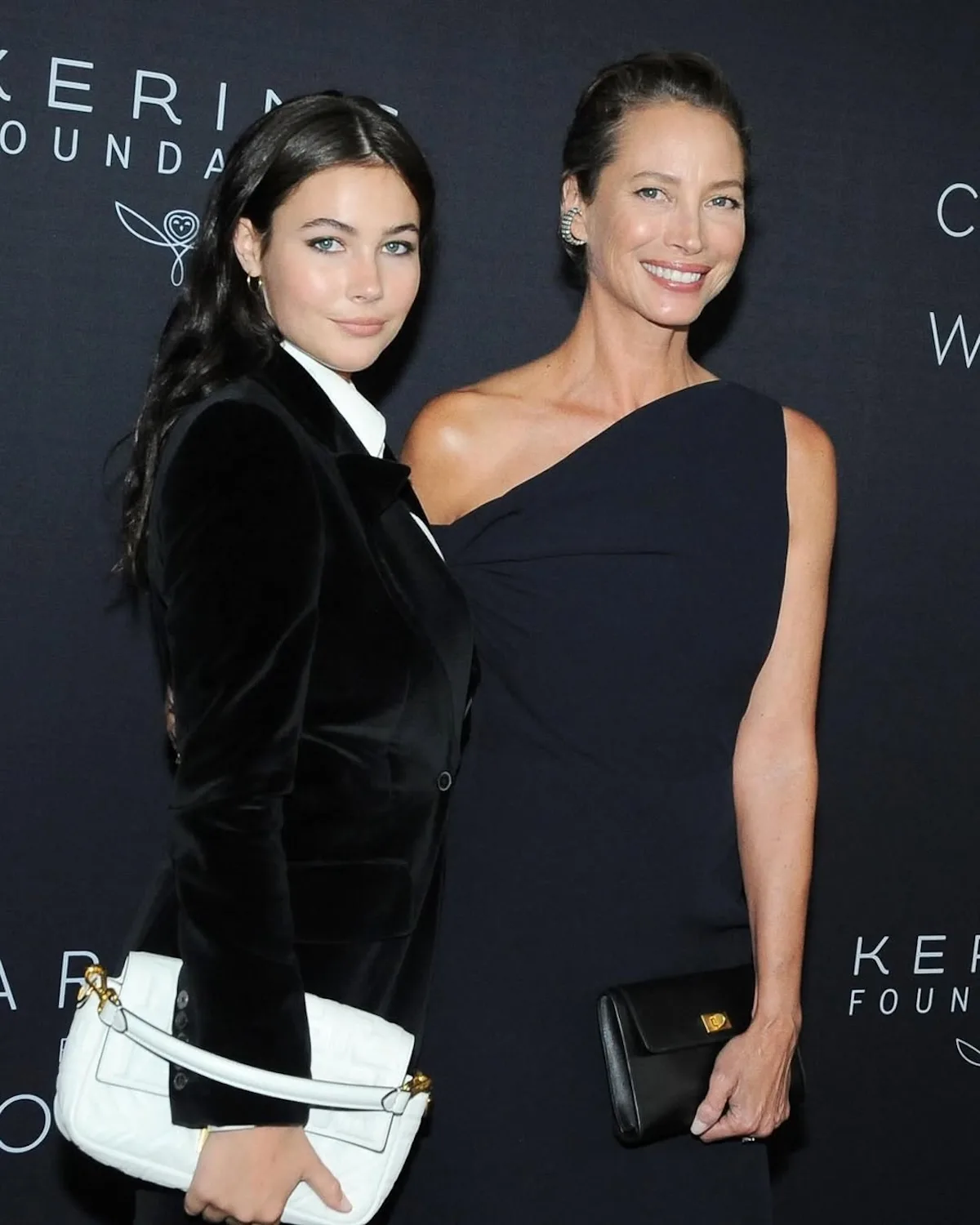Christy Turlington i Grace Burns pozują razem na czarnej ściance podczas wydarzenia. Matka i córka mają na sobie eleganckie, ciemne stylizacje.
