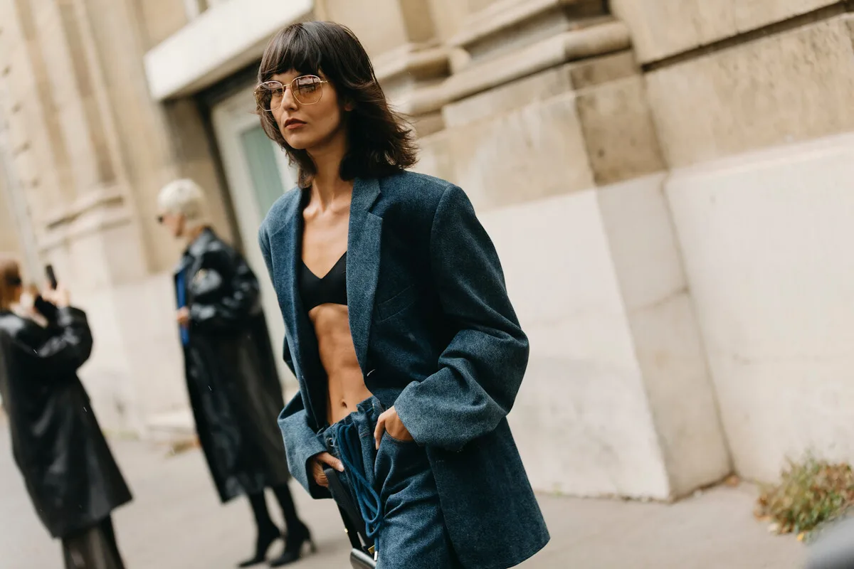UOKiK H&M Peek & Cloppenburg. Kobieta w granatowej stylizacji street fashion pozuje na ulicy podczas tygodnia mody. Zdjęcie ilustruje temat promocji i cen w sklepach odzieżowych oraz działań UOKiK wobec znanych marek modowych.