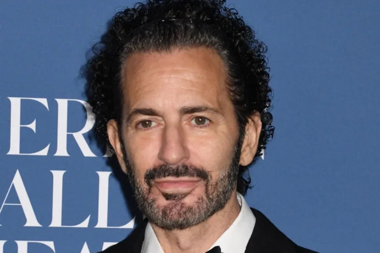 Marc Jacobs przechodzi z LVMH w ręce WHP Global. Na zdjęciu zbliżenie na projektanta Marca Jacobsa na tle niebieskiej ścianki.