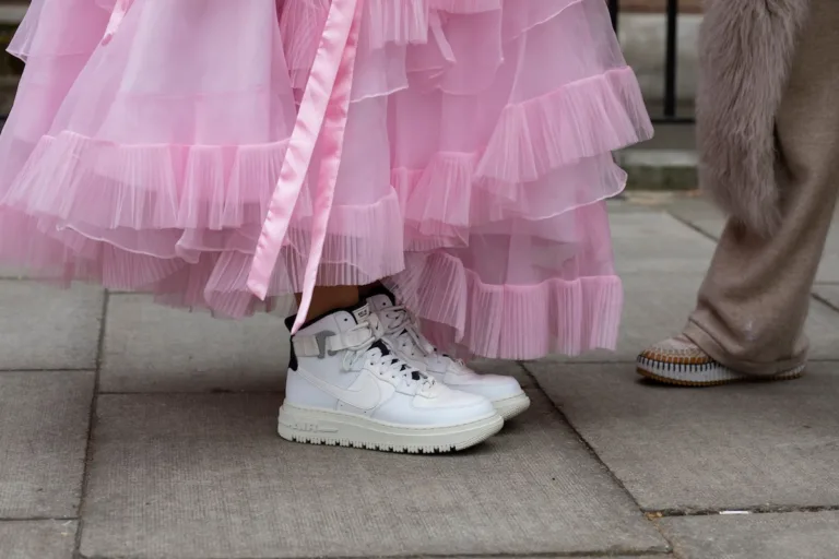 Białe sneakersy Nike Air Force 1 zestawione z różową tiulową suknią podczas street style’u. Modele Nike należą dziś do najczęściej podrabianych sneakersów 2026 i regularnie pojawiają się w raportach dotyczących rynku fake’ów.