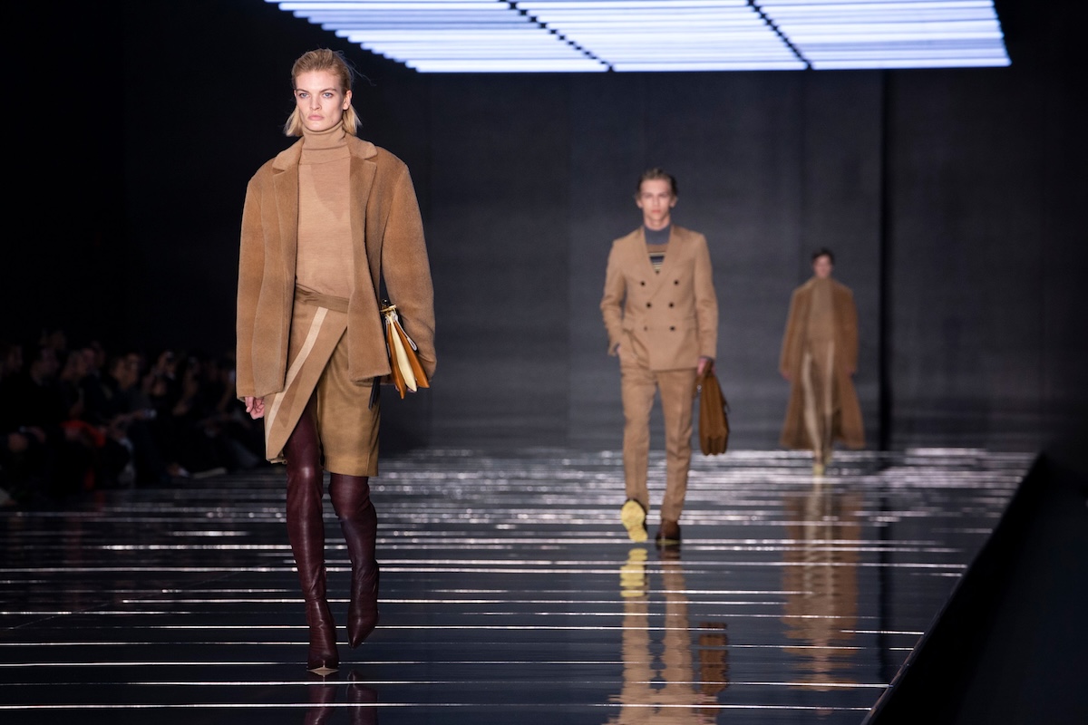 Frasers Group przejęcie Hugo Boss. Modelka w beżowej stylizacji Hugo Boss idzie po wybiegu, a za nią widać kolejne sylwetki w eleganckich płaszczach i garniturach, co podkreśla premium charakter marki będącej celem oferty Frasers Group.