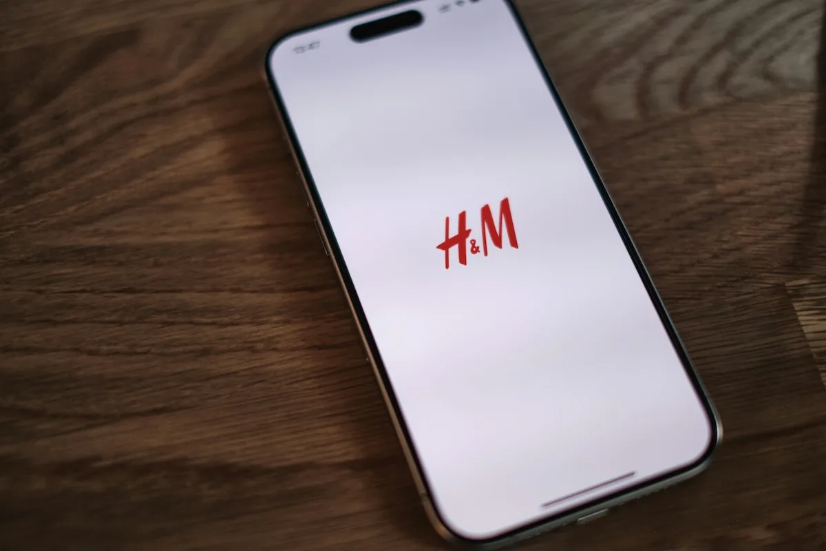 H&M wyprzedaż online 2026 - kiedy start? Na zdjęciu telefon z logo H&M na ekranie.